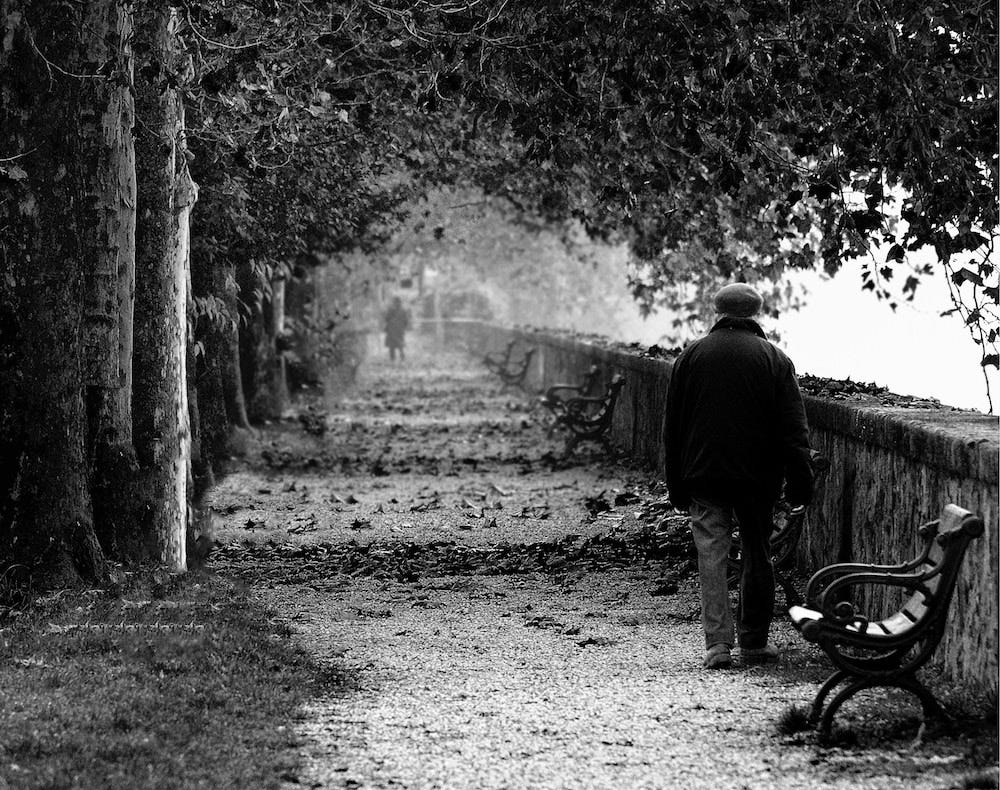 A Parisian waterfront in black and white with a man walking alongside the wall