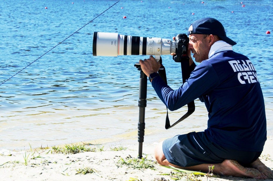sports photographer on beach pointing camera at waves