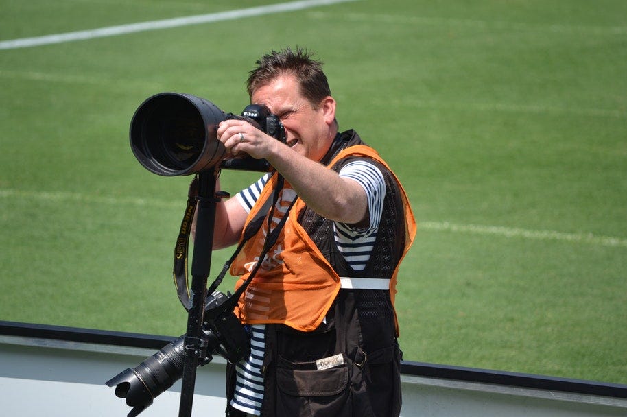 sports photographer holding camera with with zoom lens
