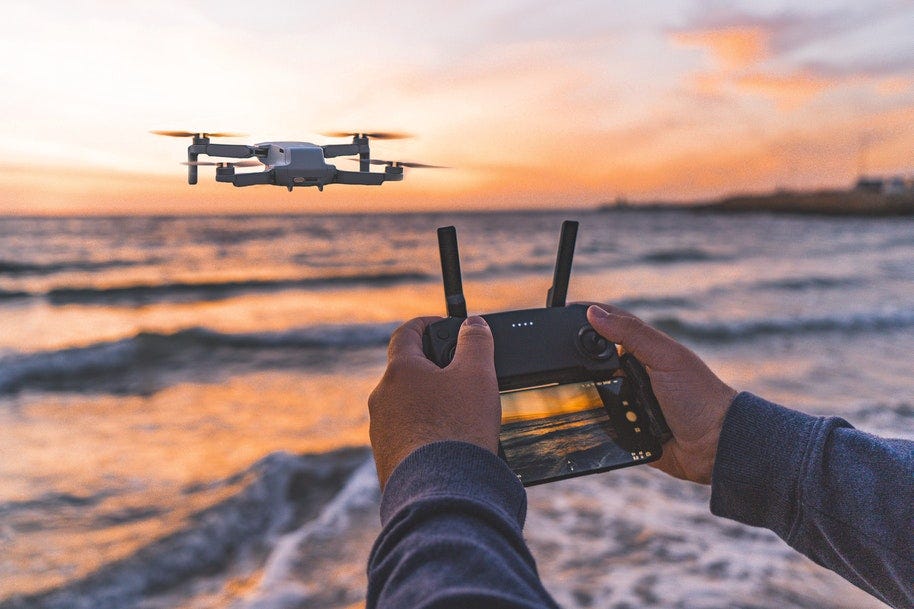 person flying drone at sunset on beach