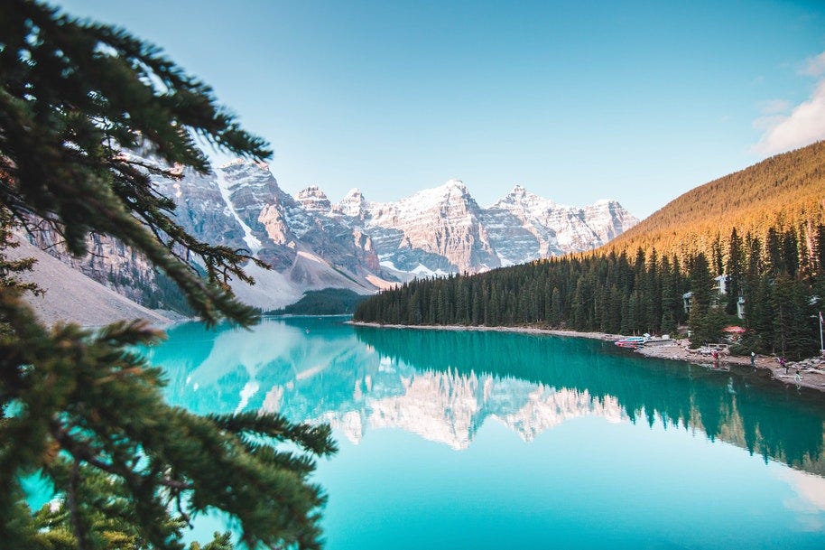 An alpine lake in the foreground with snow-capped mountains beyond