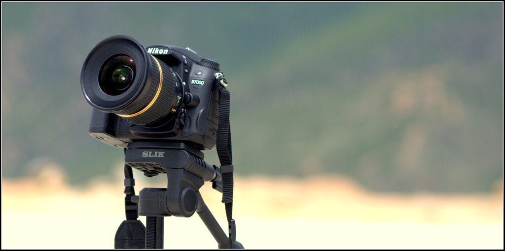 Tamron lens on a Nikon camera on a tripod with a landscape in the background.