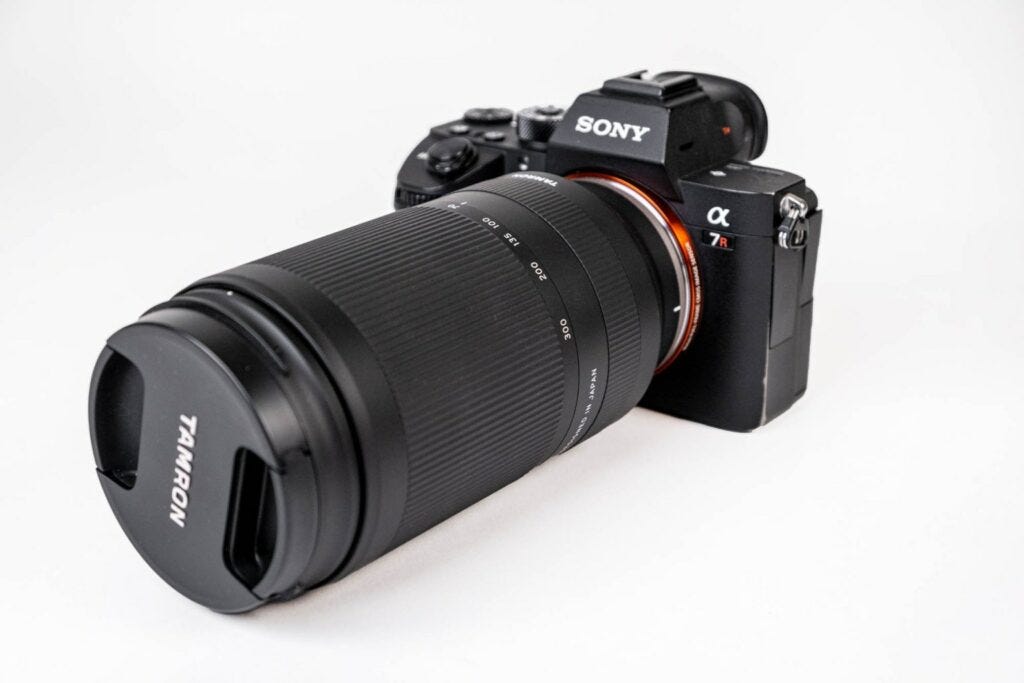 A Tamron telephoto lens on a Sony a7R camera with a white background.